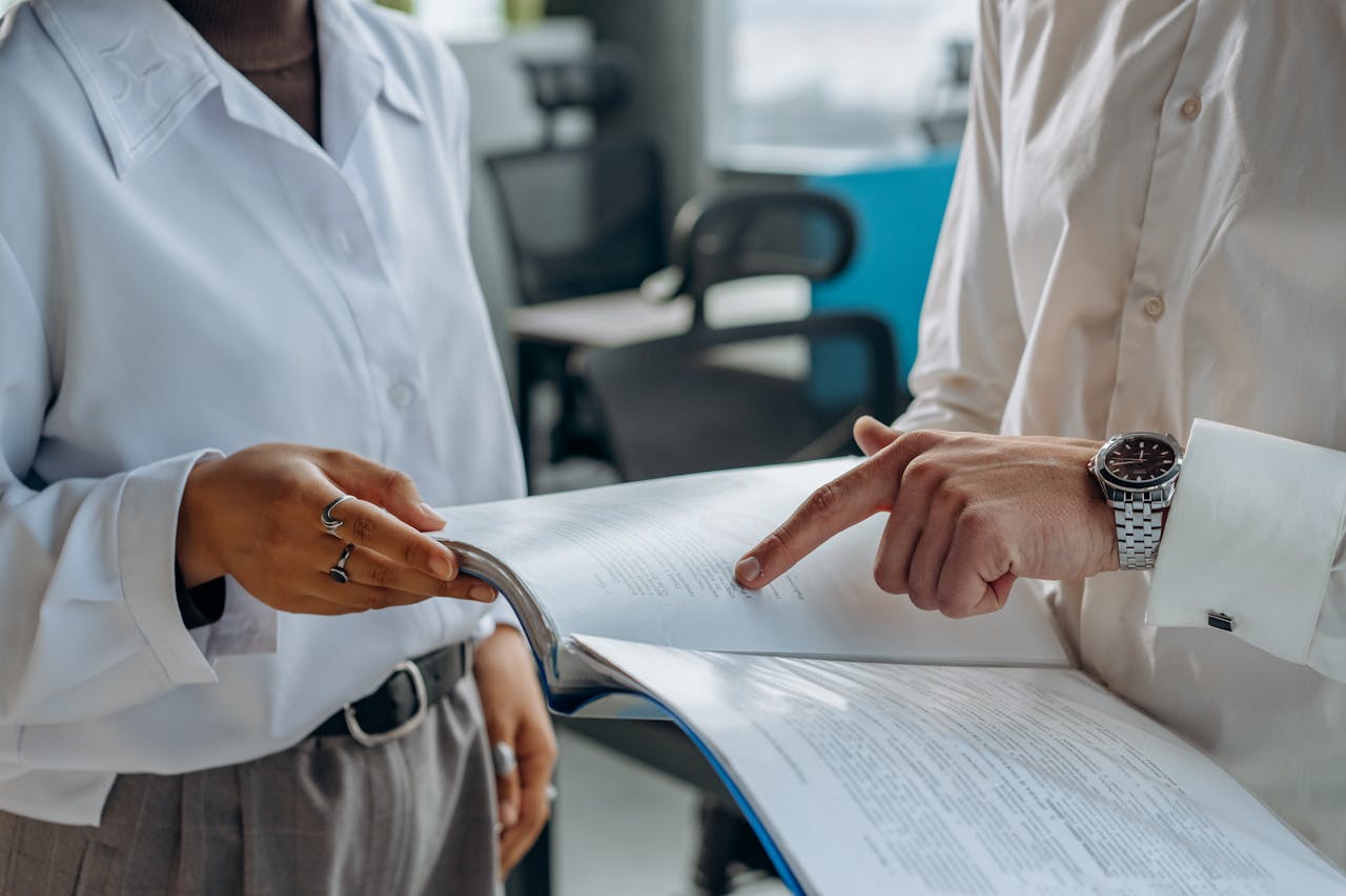 Two business professionals discussing and reviewing documents in a modern office setting.